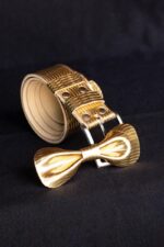 Matching set: gold leather trouser belt and gold bow tie on dark background, buckle close-up