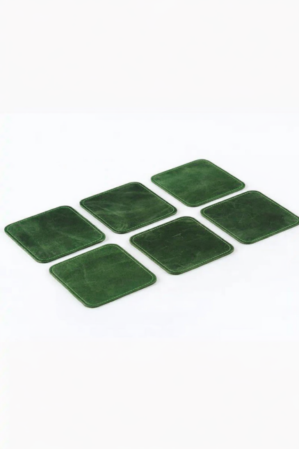 Set of six green leather coasters with stitched edges arranged on a light gray background.