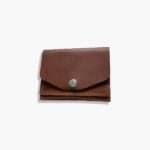 Closed leather battery holder for camera, side view showing snap-button flap.