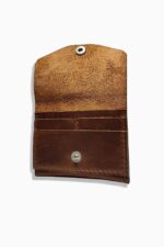 Inside view of the leather battery holder showing suede lining, snap closure, and internal pocket