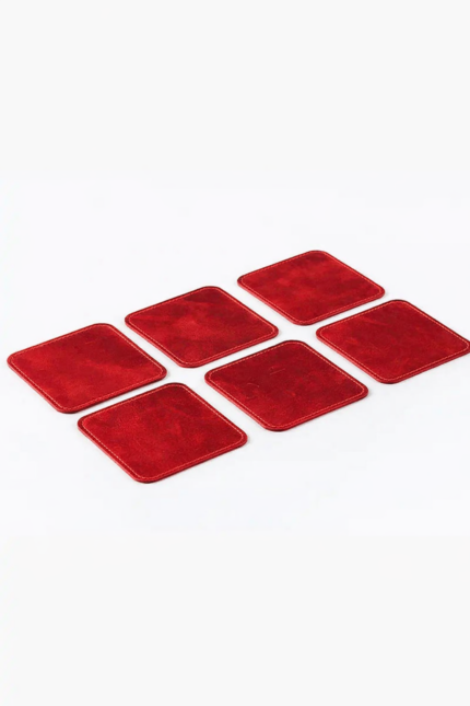 Set of six red leather coasters with stitched edges arranged on a light gray background.
