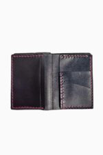 Interior view of a black leather bifold wallet opened flat and empty, showing two card pockets on the left side and two angled card slots on the right side, all finished with fuchsia pink hand-stitching, against a white background.