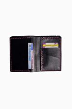 Interior view of a black leather bifold wallet opened flat, showing card slots on both sides with sample cards inserted (an Italian driver's license and a fitness-wellness card), hand-stitched edges in fuchsia pink thread, against a white background.