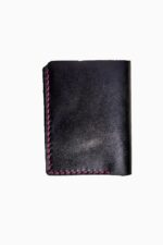 Front view of a closed black leather bifold wallet with visible fuchsia pink hand-stitching along the left side and bottom edges, showing the smooth leather grain, against a white background.