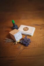 Custom wood stamp, ink pad, and dried lavender arranged on a wooden tabletop in a styled product scene.