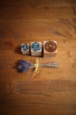 Set of custom wood stamps with engraved designs displayed beside a bundle of dried lavender on a wooden tabletop.