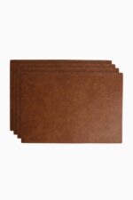 Set of four tan brown leather placemats fanned out in a staggered stack on a white background, showing the natural grain texture of the leather.