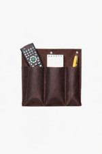Dark brown leather double wall pocket organizer holding remote controls, notepad, and pencil on a light background.