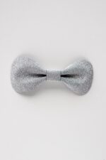 Close-up of a single silver glitter leather bow tie on a clean white background, showing the textured sparkle finish and sculpted butterfly shape.