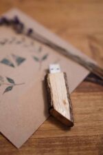 Wooden USB flash drive standing upright on a printed card with dried lavender in the background