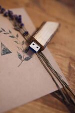 Several engraved wooden USB drives displayed beside branded wooden photo packaging and dried lavender