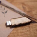 Close-up of a wooden USB drive resting on a card on a wooden surface