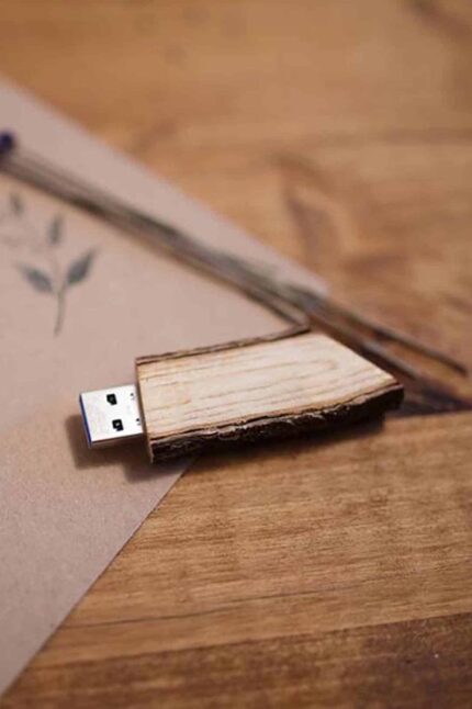 Close-up of a wooden USB drive resting on a card on a wooden surface
