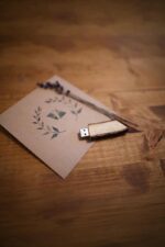 Wooden USB flash drive placed on a printed card with dried lavender on a wooden surface