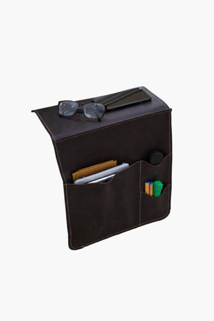Black leather wall pocket organizer holding glasses, mail, and small accessories on a light background.