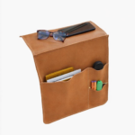 Light brown leather wall pocket organizer holding glasses, mail, and small accessories on a light background.