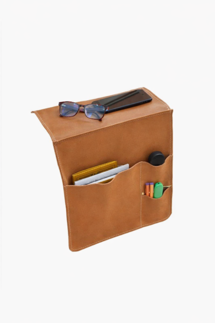 Light brown leather wall pocket organizer holding glasses, mail, and small accessories on a light background.