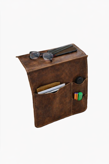 Brown leather wall pocket organizer holding glasses, mail, and small accessories on a light background.