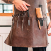 Barber holding professional scissors with a leather tool holster in a barbershop