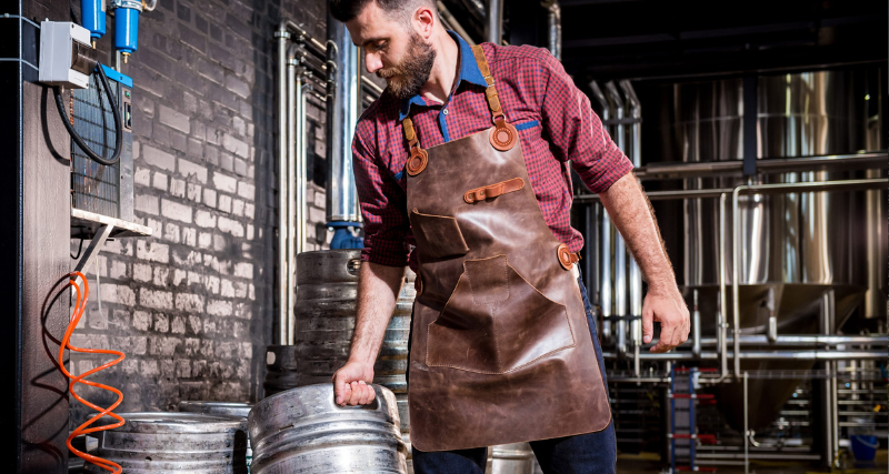 Man wearing a brown leather apron while working in a brewery