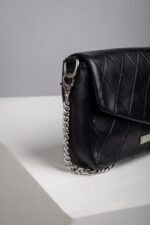 Close up of the silver chain strap on the black quilted leather bag