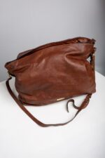 Side angle of the brown leather slouch shoulder bag showing soft body