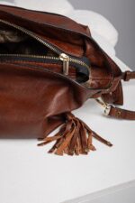 Close up of the leather tassel and gold zip detail on the brown shoulder bag