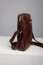 Side view of the brown leather reporter bag showing slim depth