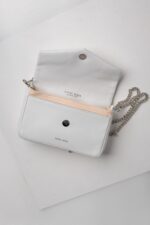 White leather chain bag opened flat showing envelope flap and snap closure