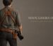 Photographer from behind wearing a leather dual camera harness and a belt with holster