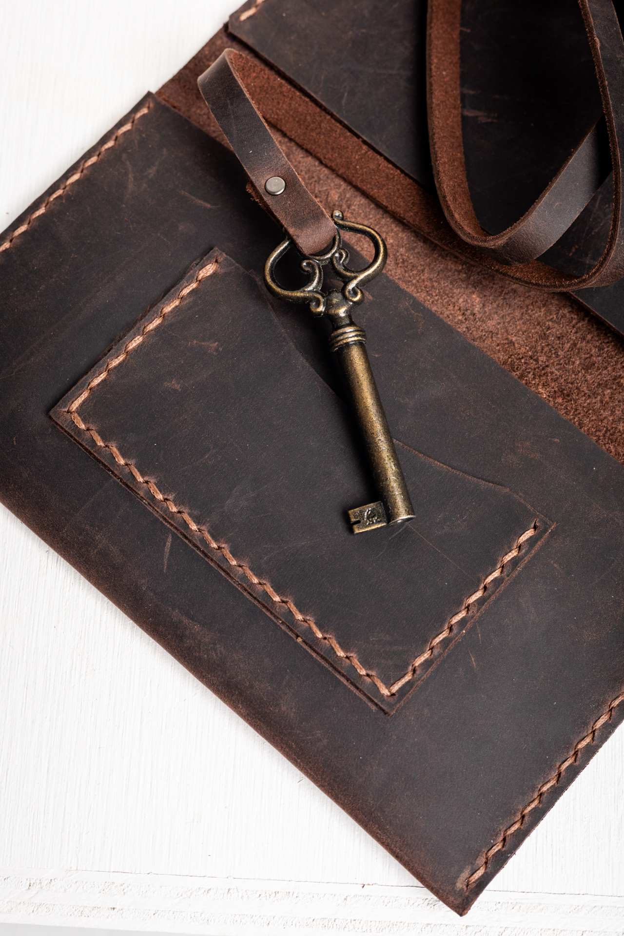 Bronze key and hand stitching detail on the leather tobacco pouch