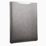Grey leather MacBook sleeve photographed at angle, showing smooth leather surface, contoured shape, and hand-opening top edge