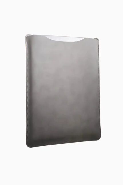 Grey leather MacBook sleeve photographed at angle, showing smooth leather surface, contoured shape, and hand-opening top edge