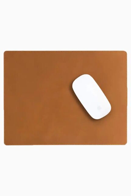 Light brown tan leather mouse pad with tone-on-tone perimeter stitching and rounded corners, with a white wireless mouse placed on the right side, top-down view on a white background.